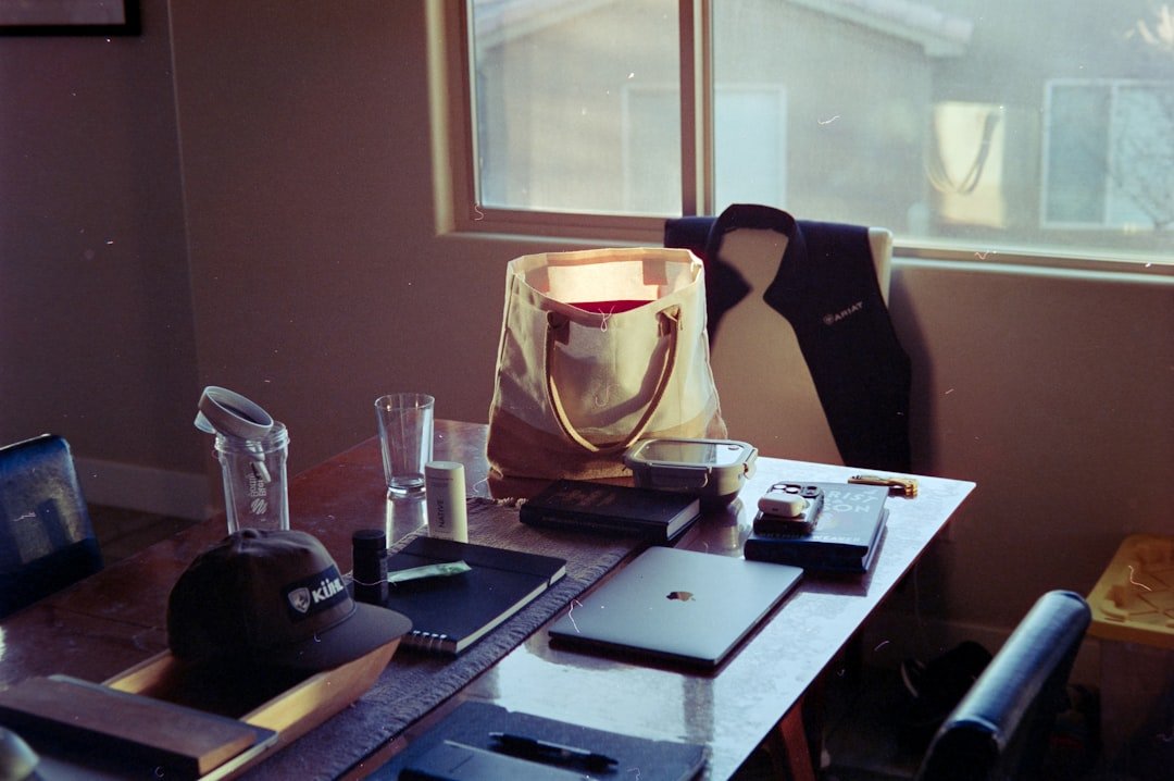 Desk with laptop, bag, and vest by window