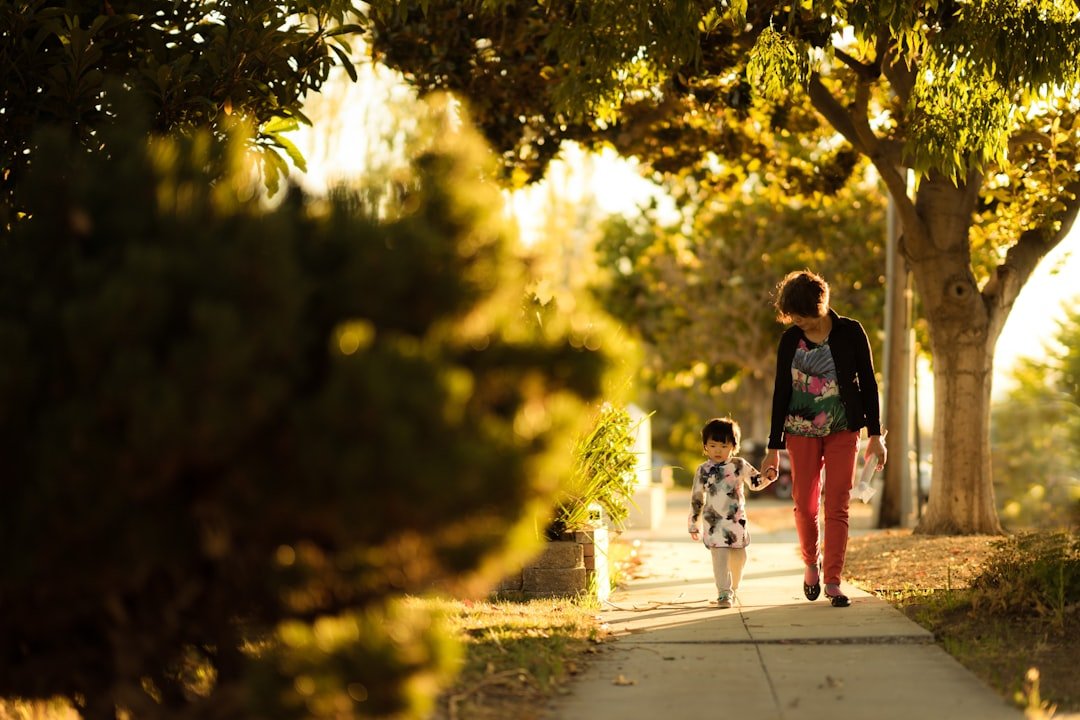 A parent and child walking together on a quiet outdoor path.