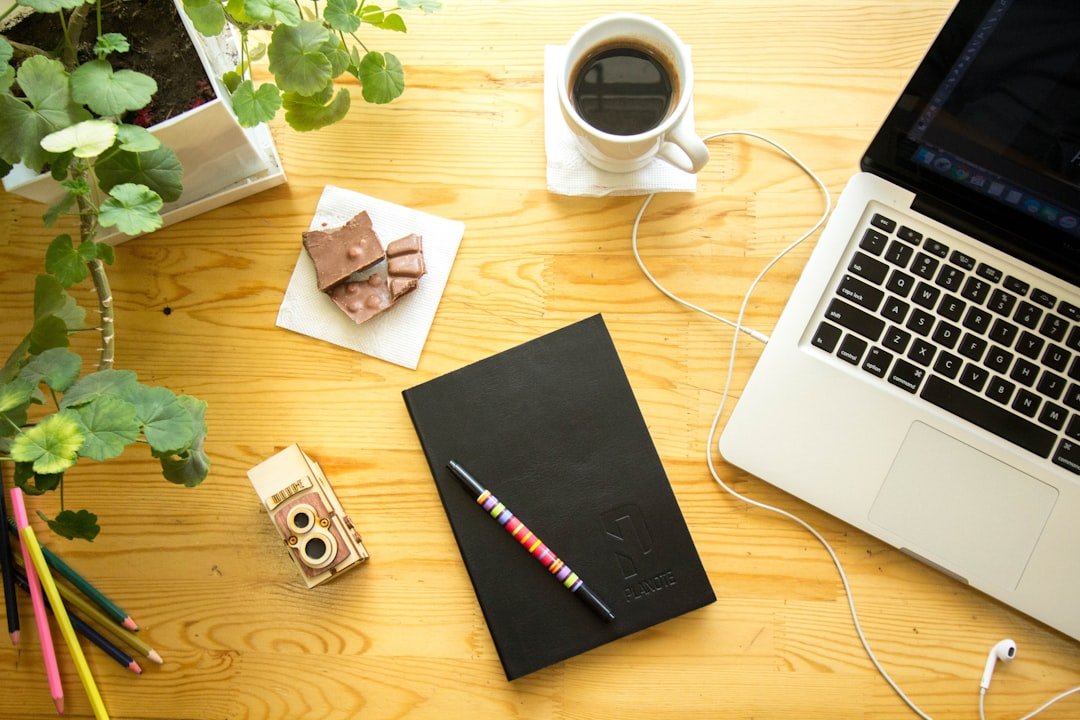 tea, notebook, plants, and a small snack on a desk